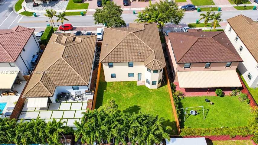 Two-story exterior featuring a hip roof, stucco facade, turret-style architectural detailing, and a fenced backyard with a lawn