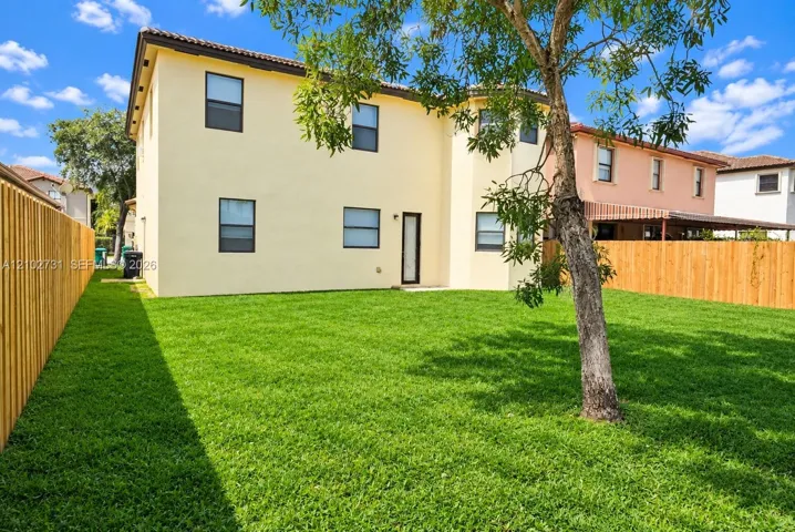 Expansive backyard featuring a manicured lawn, full-height wood fencing, and mature trees