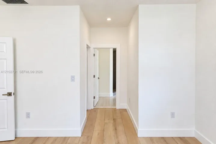 Neutral-toned walls, light-finished wood-finish flooring, recessed lighting, and white multi-panel doors with satin nickel hardware