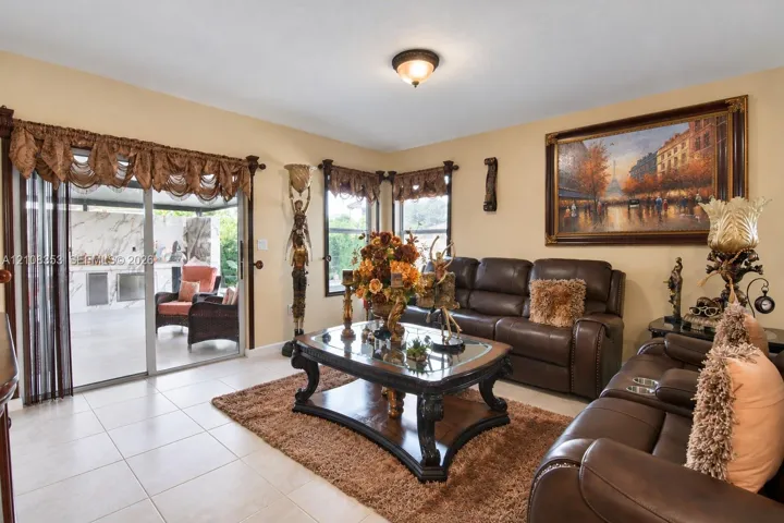 Living area featuring light-toned floor tiling, dual multi-pane windows, and a sliding glass door