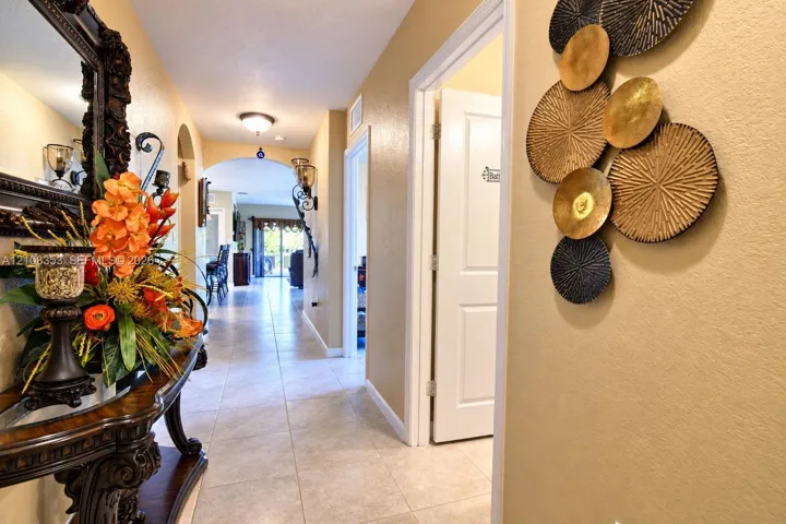 Interior hallway featuring tile flooring, arched entryways, and wall-mounted light fixtures