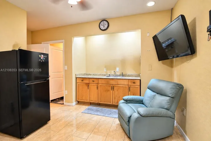 Built-in cabinetry with stone-finish countertops, stainless steel sink basin, tile flooring, and recessed ceiling lighting