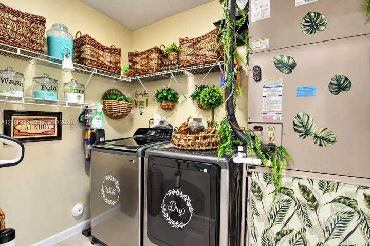 Laundry area featuring metal-finish washer and dryer, white wire wall-mounted shelving, and an enclosed HVAC unit