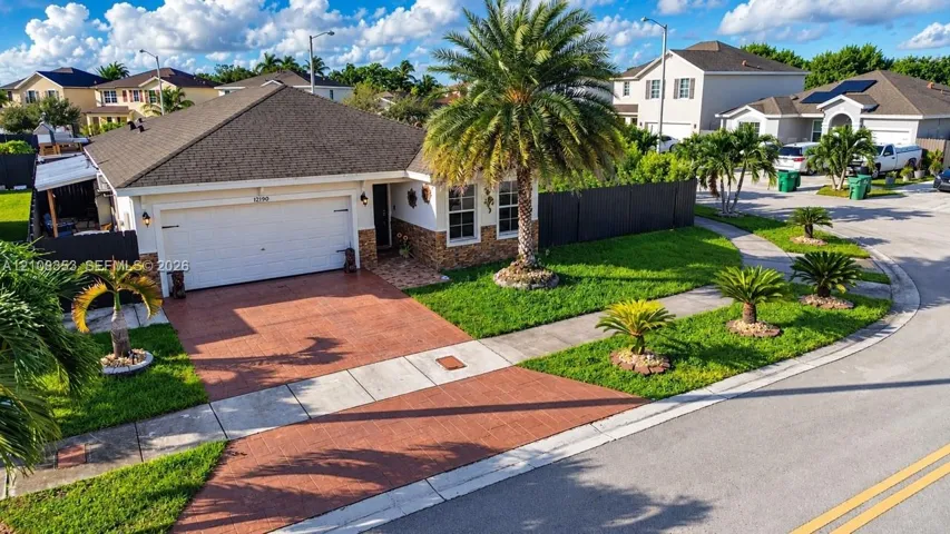 Single-story residence featuring a hipped roof, attached two-car garage, stone-veneer facade accents, and a paved driveway