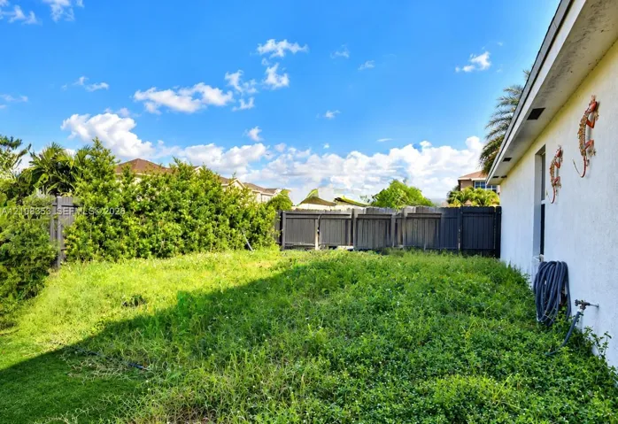Rear yard featuring dark-toned privacy fencing, mature hedge borders, and an exterior water spigot