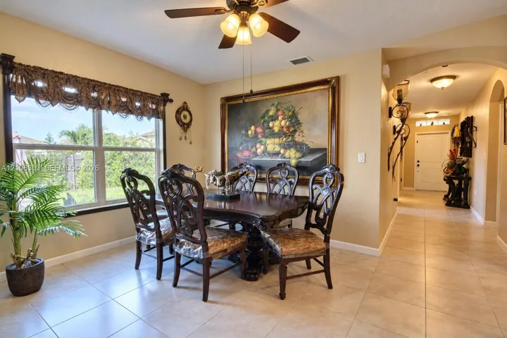 Ceramic tile flooring, neutral wall tones, arched architectural details, ceiling fan with integrated lighting, and expansive window with casing