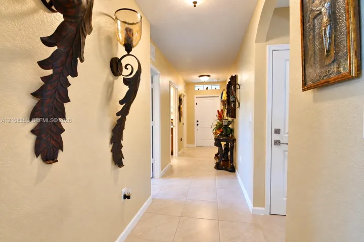 Hallway featuring tile flooring, archway detailing, and decorative wall-mounted light fixtures