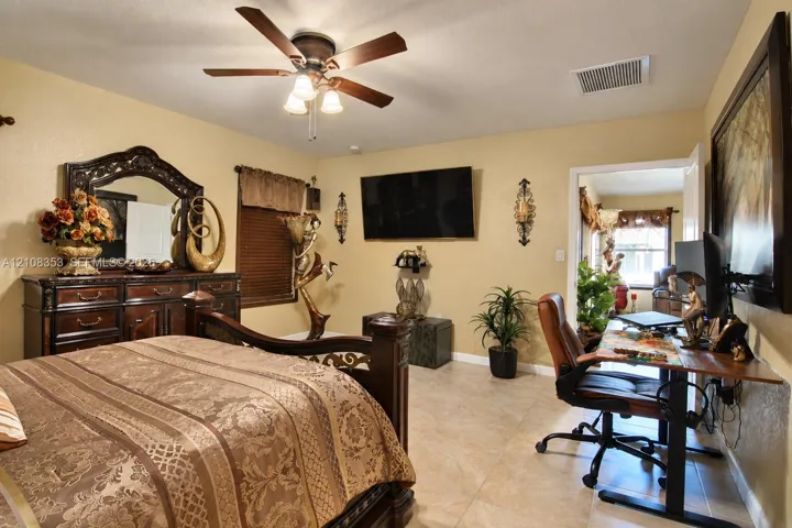 Neutral-toned interior space featuring light-colored tile flooring and a multi-blade ceiling fan with integrated lighting