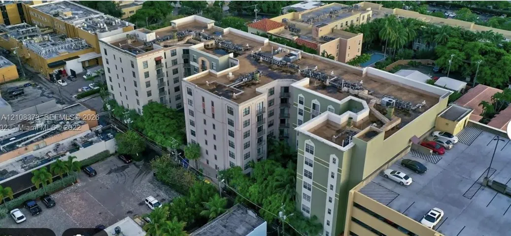 Multi-story complex featuring a structured exterior, arched window details, dedicated surface parking, and manicured perimeter landscaping