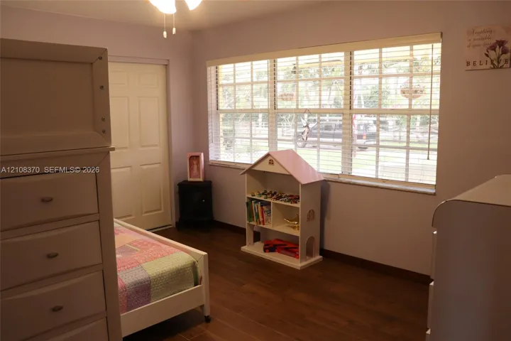 Wood-finish flooring, multi-pane window with integrated blinds, and ceiling fan with integrated lighting fixture