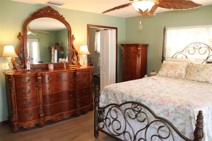 Room featuring wood-finish flooring, a ceiling fan, and louvered closet doors