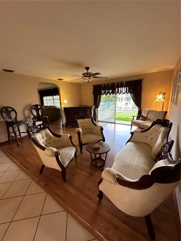 Raised wood-finish flooring, tile flooring, arched wall opening, and sliding glass doors