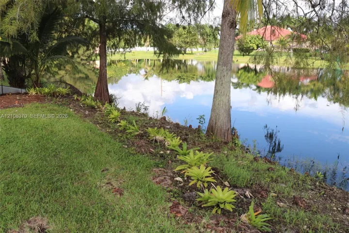 Waterfront lot featuring mature trees, landscaped border plantings, and expansive lawn