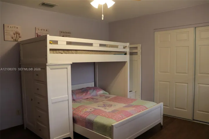 Double-door closet with paneled trim, wood-finish flooring, and a ceiling-mounted light fixture