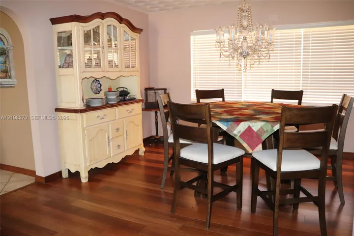 Wood-finish flooring, crystal-style chandelier, and an arched wall opening
