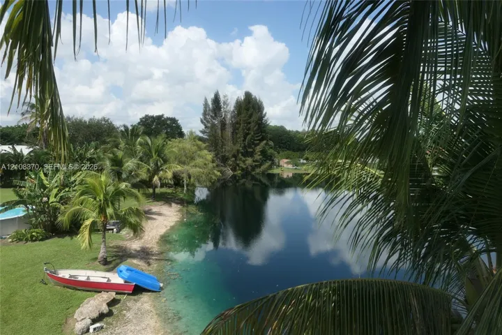 Waterfront property featuring a private shoreline, expansive grassy lawn, and mature palm trees