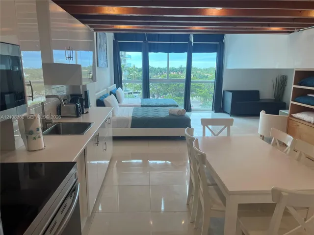 High-gloss cabinetry, stainless steel sink, tile flooring, exposed wood ceiling beams, and floor-to-ceiling windows