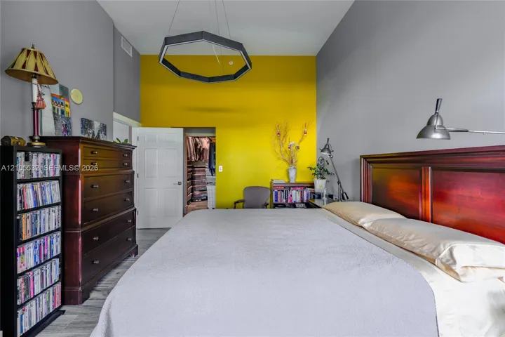 High-ceilinged room featuring a geometric pendant light fixture, a wood-panel door, and wood-finish flooring