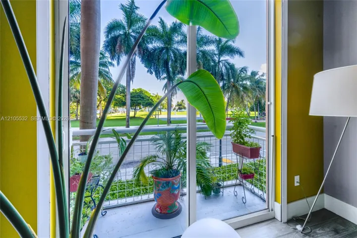 Floor-to-ceiling sliding glass door with a metal-railed balcony featuring exterior hardscaping