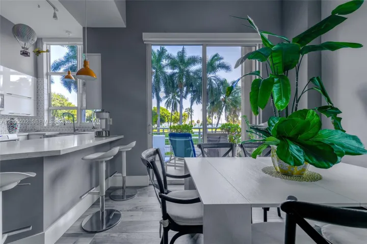 Kitchen featuring white cabinetry, quartz countertops, a geometric tile backsplash, wood-finish flooring, and sliding glass doors with exterior access