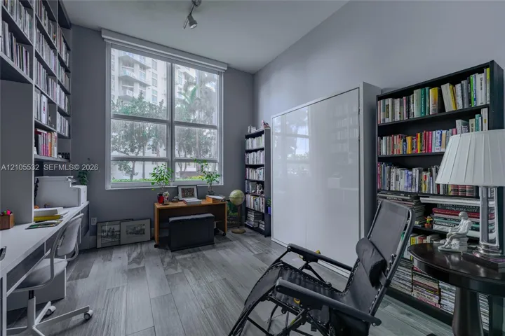 Large picture window with natural illumination, built-in floor-to-ceiling shelving, wall-integrated cabinetry, and wood-finish flooring