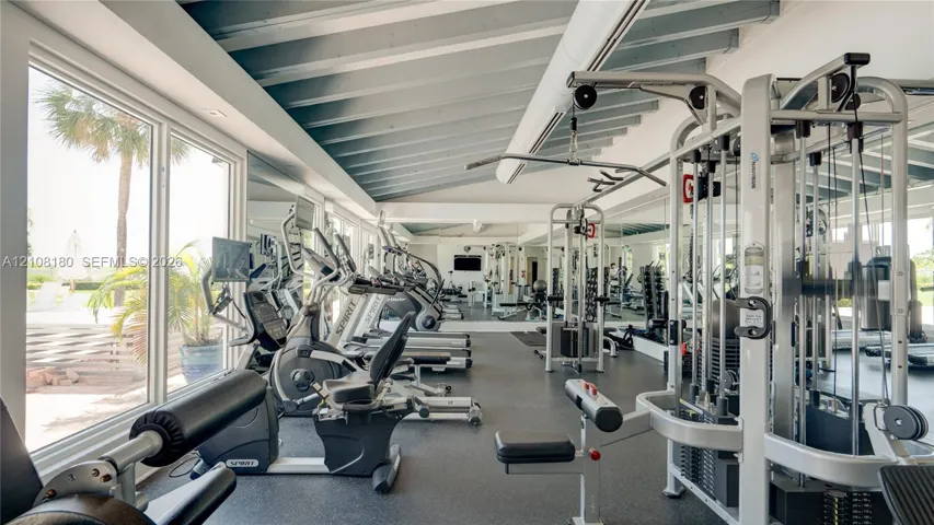 Exercise room featuring high sloped ceilings with exposed rafters, floor-to-ceiling windows, rubberized flooring, and full-length wall mirrors