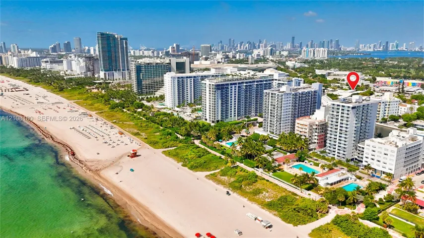 Aerial perspective of a multi-story residential building located in a coastal urban environment featuring immediate proximity to the Atlantic shoreline and surrounding high-rise infrastructure