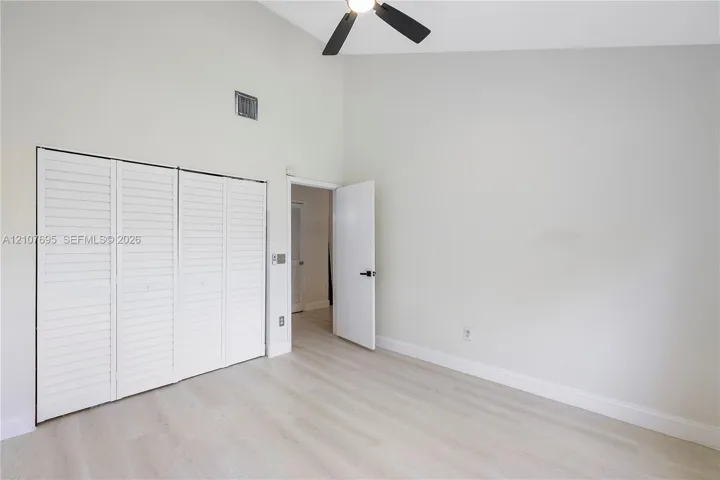 Vaulted ceilings, wood-finish flooring, four-panel louvered closet doors, and a ceiling-mounted light fixture