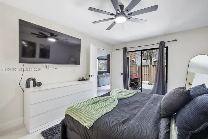 Multi-blade ceiling fan with integrated lighting, sliding glass door with dark metal hardware, and neutral wall tones