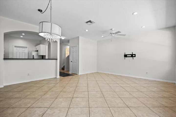 Another view of the versatile living and dining space with a modern light fixture and neutral finishes.
