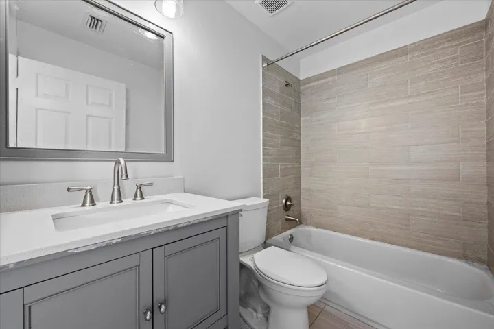 Full bathroom with double-sink vanity, tub and shower combination, and tile finishes.