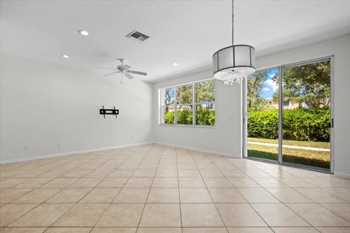Spacious, open living area with tile flooring, natural light, and sliding glass doors.