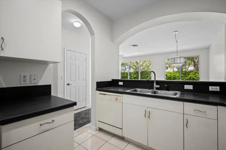 Additional view highlighting the countertop space, cabinetry, and arched opening to the living area.