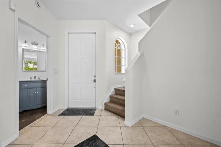 Bright entryway with tile flooring, staircase, and access to the kitchen.