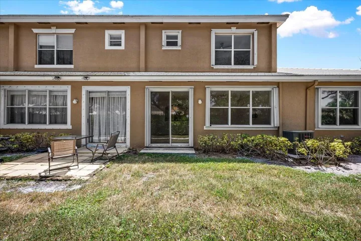 Rear view of the townhome with sliding glass doors, large windows, and a backyard area.