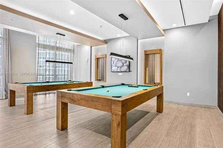 Recessed tray ceilings with integrated lighting, wood-finish flooring, and built-in wall-mounted cue racks