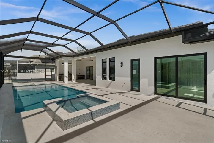 Screened-in lanai featuring a swimming pool, integrated spa with tile detailing, paved flooring, and glass sliding doors