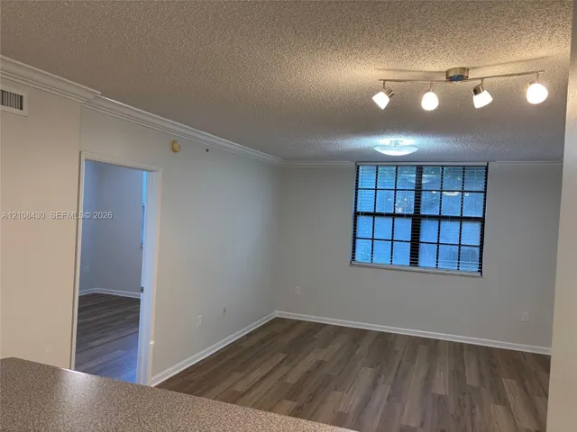 Living area featuring wood-finish flooring, crown molding, multi-bulb adjustable track lighting, and a multi-pane window