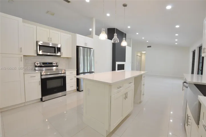 Kitchen featuring white shaker-style cabinetry, quartz countertops, stainless steel appliances, a central island, and recessed lighting