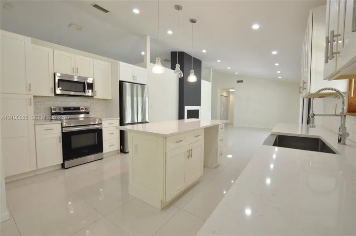 Kitchen featuring white Shaker-style cabinetry, quartz countertops, a central island, stainless steel appliances, and tile flooring