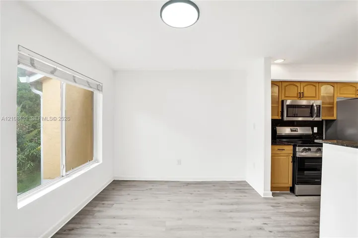 Wood-finish flooring, large sliding window, recessed lighting, and built-in cabinetry featuring stone countertops and stainless steel appliances
