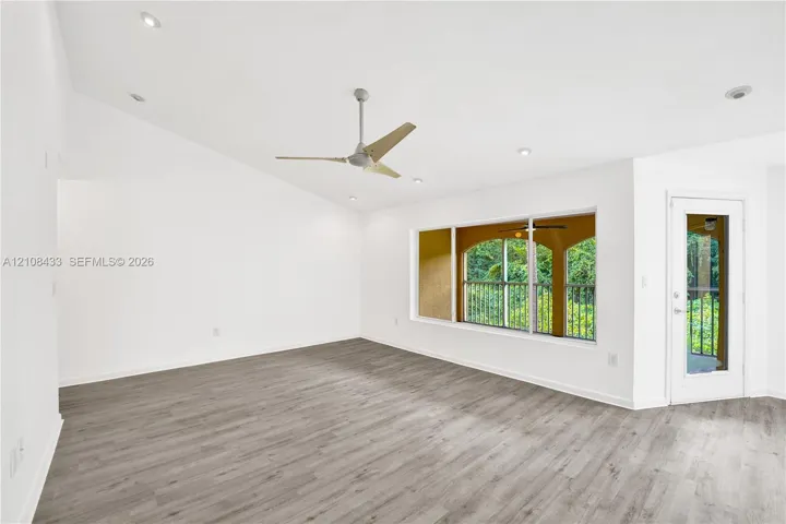 Vaulted ceilings featuring recessed lighting, wood-finish flooring, a contemporary ceiling fan, and a glass-paneled exterior door