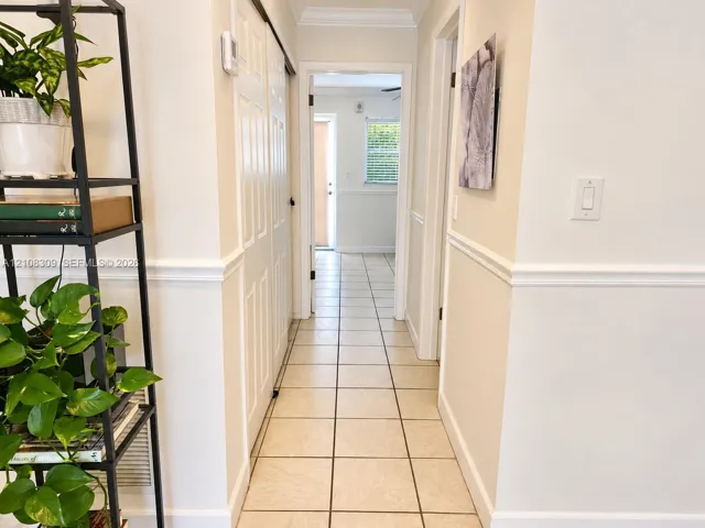 Hallway featuring neutral-toned tile flooring, chair rail molding, and white paneled sliding closet doors