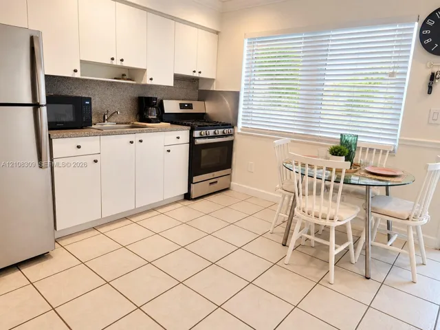 Kitchen featuring white cabinetry, stone-finish countertops, stainless steel appliances, and tile flooring