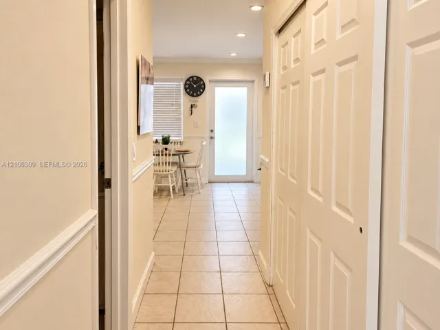 Interior hallway featuring tile flooring, recessed lighting, chair rail molding, and a paneled sliding closet door, finished with a glass-paneled exterior door