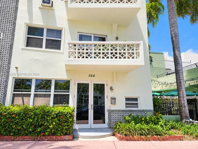 Exterior facade featuring decorative concrete masonry screen walls, private balcony, glass-paneled double entry door, and manicured landscaping with brick edging