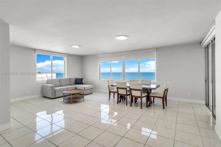 Open-concept living space featuring high-gloss tile flooring, floor-to-ceiling windows, and panoramic ocean water scenery