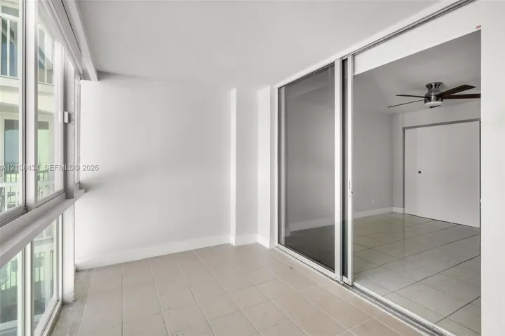 Enclosed sunroom featuring expansive multi-pane windows, large-format tile flooring, and a sliding glass door system