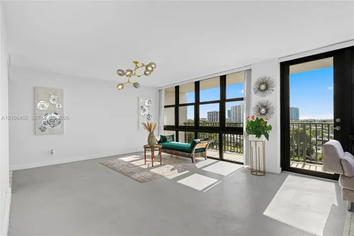 Open-concept interior featuring floor-to-ceiling windows, polished concrete flooring, a multi-arm modern light fixture, and a private balcony access door
