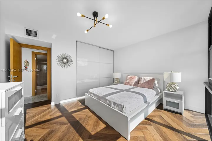 Herringbone wood-finish flooring, floor-to-ceiling built-in gloss cabinetry, and a multi-arm geometric light fixture with matte black and brass finishes